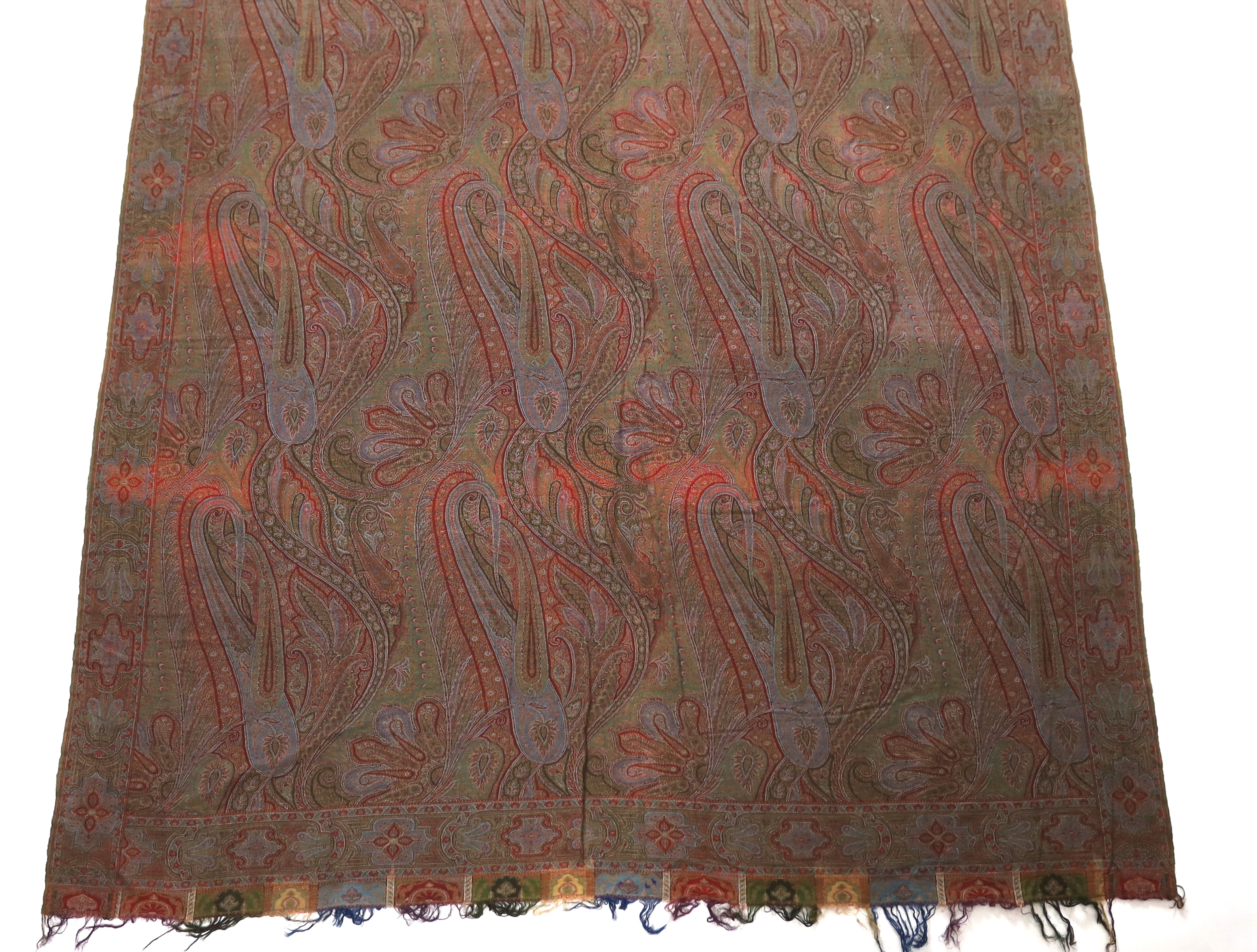 An 1860’s-70’s Scottish Paisley wool shawl, woven with multi coloured wools in a large scrolling teardrop design, bordered and fringed both ends 165cm wide x 345cm long